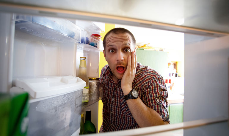 a surprised man opening his fridge