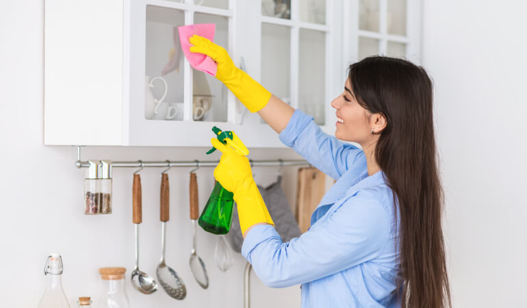 Woman cleaning kitchen cabinets