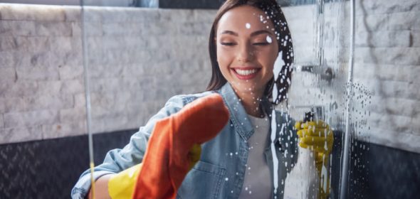 Woman cleaning shower screen in bathroom