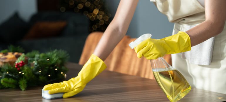 Woman cleaning wooden table with homemade Christmas cleaning spray